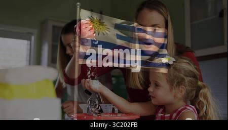 Mother and daughters pouring flour, mixing batter in home kitchen with red bowl and flag overlay Stock Photo