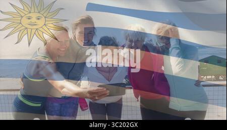 Smiling friends in sportswear taking smartphone selfie on beach railing, with lifeguard tower Stock Photo