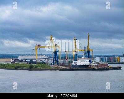 Belfast, UK - Jun 15 2025: The formidable Harland and Wolff cranes tower over the shipyard in Belfast, UK, under a dramatic cloudy sky. Stock Photo