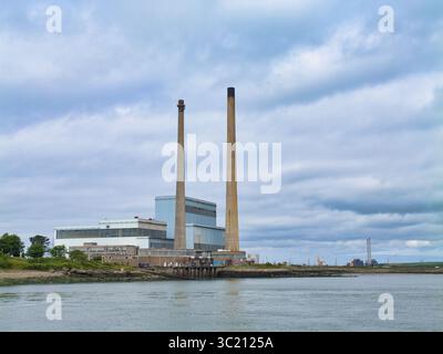 Tarbert, Ireland - Jun 10 2025: The Tarbert Power Station stands prominently by the water under a dramatic cloudy sky in Tarbert, Ireland. Stock Photo