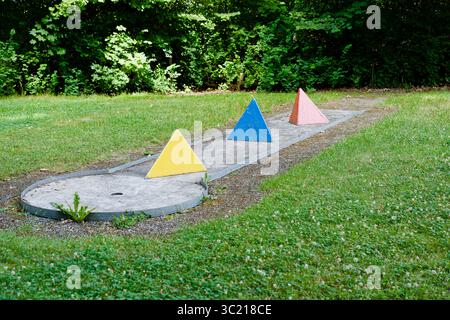 mini golf course with colorful cone-shaped obstacles, surrounded by grass and trees on a sunny summer day. Stock Photo