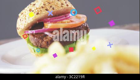 Sesame seed bun burger sitting on white plate in studio with fries, floating shapes, copy space Stock Photo