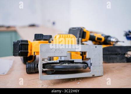 Professional-grade circular saw and cordless drill lie on a workbench amidst sawdust, indicating ongoing carpentry work, likely part of a kitchen renovation or other home improvement project Stock Photo
