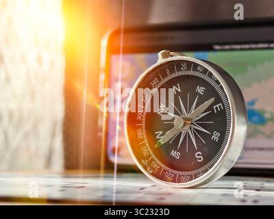 A close-up shot of a person holding a vintage-style compass with a metallic finish and clear markings for cardinal directions (N, S, E, W) and degree Stock Photo