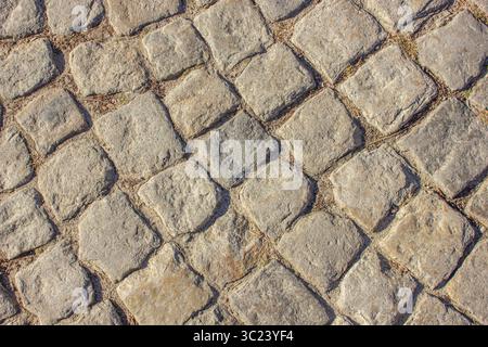 Cobblestone pavement background. Pavement road background. Bricks road. Brick surface background. Rough brick road Textured background. Sidewalk. Old Stock Photo