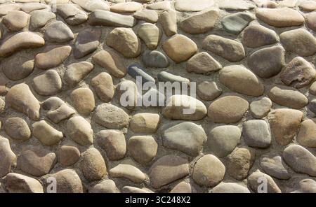 Abstract background with round pebble stones. Wall round stone rock texture or background. Stock Photo