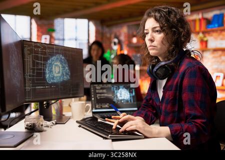Programmer coding in fast paced AI startup office, building scalable solutions for businesses. AI industry startup technician leveraging machine learning technology in workspace Stock Photo