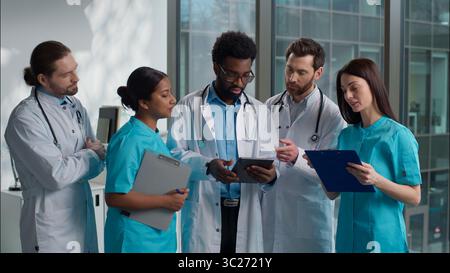 Happy smiling professional multiethnic diverse doctors people medicare team portrait five interns men women talking discuss health exam result looking Stock Photo