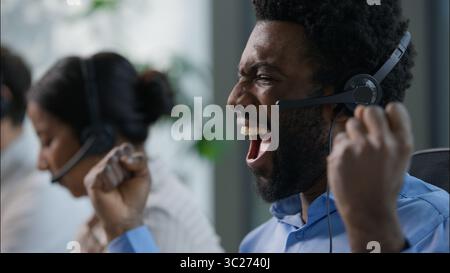 Business people multiethnic call center operators worker African American man headset scream shouting yes celebrating triumph help line consultation Stock Photo