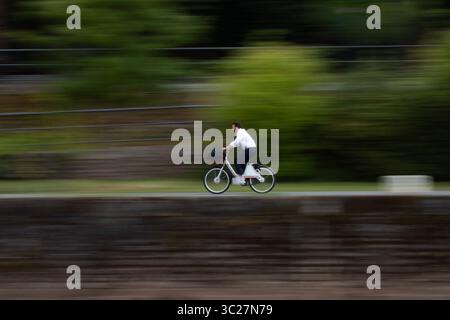 Frankfurt, Hesse, Germany. 23rd July, 2025. A man rides a bicycle along the Main River promenade in Frankfurt, Germany. Photo captured with slow shutter speed. (Credit Image: © Matias Basualdo/ZUMA Press Wire) EDITORIAL USAGE ONLY! Not for Commercial USAGE! Stock Photo