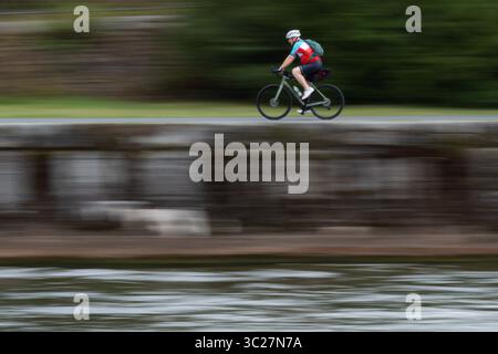 Frankfurt, Hesse, Germany. 23rd July, 2025. A man rides a bicycle along the Main River promenade in Frankfurt, Germany. Photo captured with slow shutter speed. (Credit Image: © Matias Basualdo/ZUMA Press Wire) EDITORIAL USAGE ONLY! Not for Commercial USAGE! Stock Photo