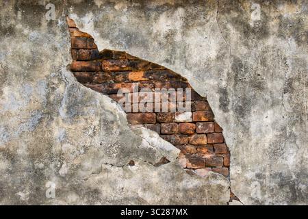 Texture of an old concrete wall with exposed bricks offering a grunge style background for urban decay themes and structural detail. Stock Photo