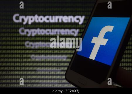May 24, 2019 - Asuncion, Paraguay - Facebook logo icon is seen on a smartphone screen against the text cryptocurrency and binary code text unfocused on background. (Credit Image: © Andre M. Chang/ZUMA Wire) Stock Photo