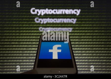 May 24, 2019 - Asuncion, Paraguay - Facebook logo icon is seen on a smartphone screen against the text cryptocurrency and binary code text unfocused on background. (Credit Image: © Andre M. Chang/ZUMA Wire) Stock Photo