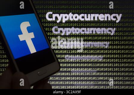 May 24, 2019 - Asuncion, Paraguay - Facebook logo icon is seen on a smartphone screen against the text cryptocurrency and binary code text unfocused on background. (Credit Image: © Andre M. Chang/ZUMA Wire) Stock Photo