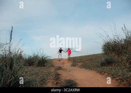 Couple walks hand-in-hand on path. Journey of love in vast landscape. Adventure and connection. Stock Photo