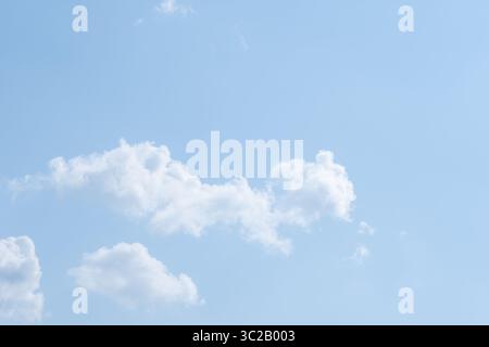 Fluffy white clouds scattered across bright blue sky on sunny day. concept of peace and calm. Stock Photo