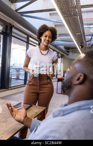 African American coworkers engaging in discussion in coworking space with tablet and coffee cup Stock Photo