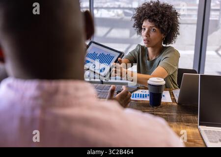African American coworkers presenting charts on tablet in office with laptops, copy space Stock Photo