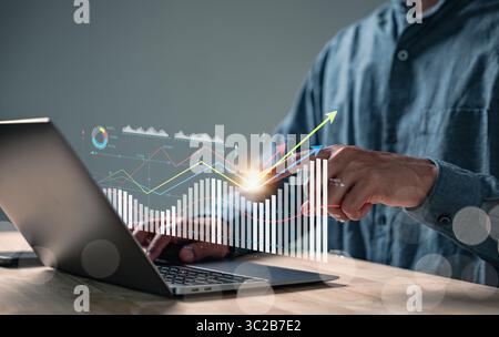 Analyzing data market performance for a business report with KPI metrics, a businessman uses a laptop to visualize rising financial trends and growing Stock Photo