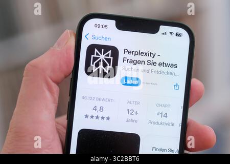A cell phone with the Apple App Store page open shows the Perplexity app for download. Stock Photo
