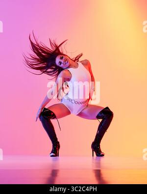 Jazz funk performer dressed in white attire wearing high heels with vibrant backdrop Stock Photo
