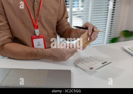 an accountant is working on company's number in the office, this employee works in account department, the businessman uses calculator to calculate pr Stock Photo