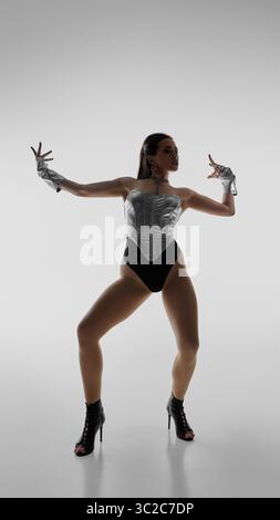 Elegant dancer striking dynamic pose in high heels against plain background Stock Photo