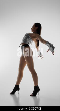 Dancer in silhouette striking pose wearing high heels and stylish dancewear Stock Photo