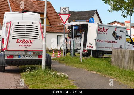 July 14, 2025 - Klockenhagen-Germany: Two technicians work on a sewer cleaning robot beside service vans, with a foot and bike path in the foreground Stock Photo