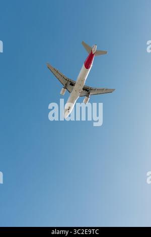 A twin-engine passenger plane descends before landing at an airport. Stock Photo