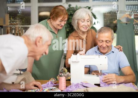 Retired students learning sewing from male instructor in tailoring workshop Stock Photo