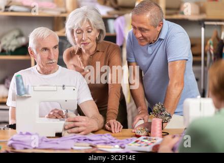Retired students learning sewing from male instructor in tailoring workshop Stock Photo