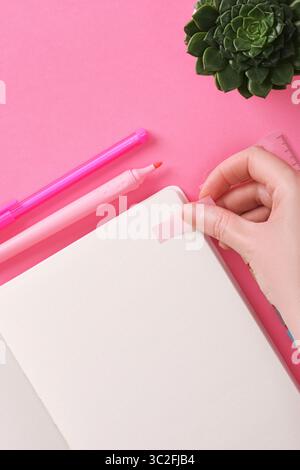 Hand sticks a sticky note in an open notebook with a blank page. Stock Photo