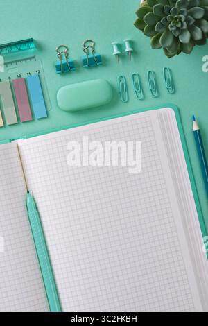 Top view of a desk with mint-colored stationery and an open notepad. A place for your text. Stock Photo