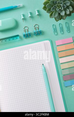 Top view of a desk with mint-colored stationery and an open notepad. Place for your text. Stock Photo