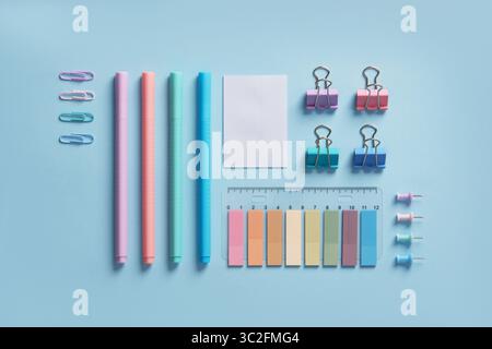Pastel-colored stationery neatly arranged on a light blue background. Workplace organization. Back to school concept. Stock Photo