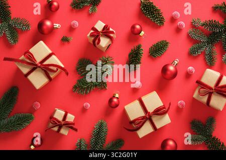 Christmas background with green pine sprigs, gift boxes and red Christmas baubles. Red background. Stock Photo