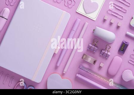 Stationery background with pastel purple supplies, notepad, paper clips, scissors, sticky notes, felt tip pens, eraser, stapler, ruler, pins Stock Photo