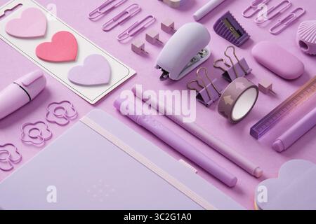 Stationery background with pastel purple supplies, notepad, paper clips, sticky notes, felt-tip pens, eraser, stapler, ruler, pins. Selective Focus. Stock Photo