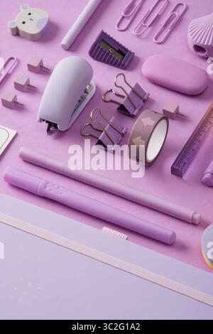 Stationery background with pastel purple supplies, notepad, paper clips, stickers, felt-tip pens, eraser, stapler, ruler, pins. Selective Focus. Stock Photo