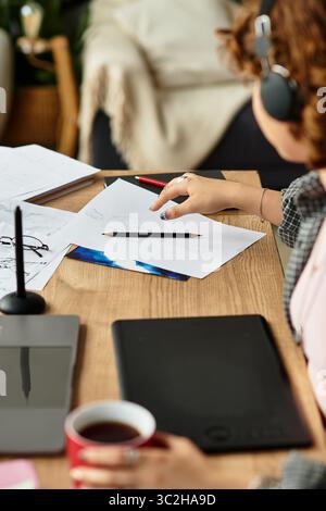 Young woman engages in freelance work at home, focusing on details while using graphic tablet Stock Photo