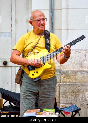 Buddhist singer and guitar player performing on street on market day - Loches, Indre-et-Loire (37), France. Stock Photo
