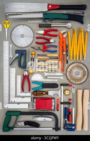 Flat lay of old hand tools on concrete background. Large collection of various rusty tools and bits arranged on concrete. Stock Photo