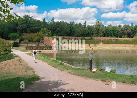 Markshall Estate Essex, view of a visitor to Markshall Estate walking past the lake and heading towards the old walled garden, Coggeshall, England,UK Stock Photo