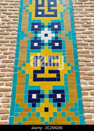 Vibrant tile mural features intricate geometric patterns on a textured brick wall, showcasing artistic design and craftsmanship Stock Photo