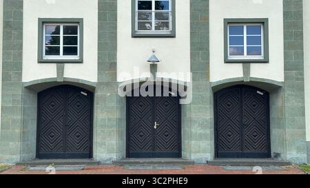 Three detailed wooden doors with ornate carvings set in arched stone frames of former British Army building, Herford, Germany. Stock Photo
