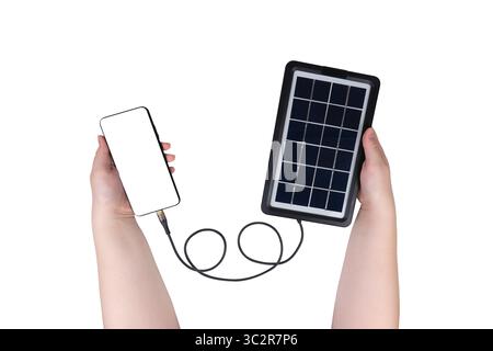 Hands holding smartphone connected to portable solar panel with USB cable on white background Stock Photo