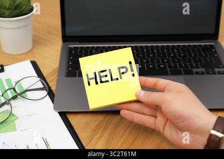 Man holding paper notes with word Help at workplace, closeup Stock Photo