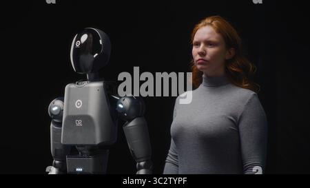 VFX Animation of Futuristic People and Robots Concept: Visualization of Young Woman Standing with Advanced Humanoid Robot. Collaboration and Connection Between Humanity and Artificial Intelligence. Stock Photo